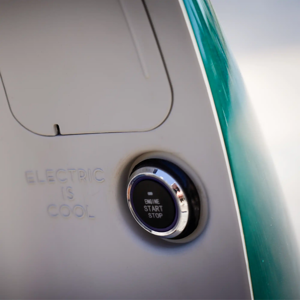 A képen a Zöld NITO NES 10 indítógombja látható. Mellette az "Electric is Cool" szöveg található, csupa nagybetűvel kiírva.