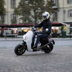 NITO NES 5 elektromos robogó használat közben városi környezetben, fehér karosszériával és barna üléssel.