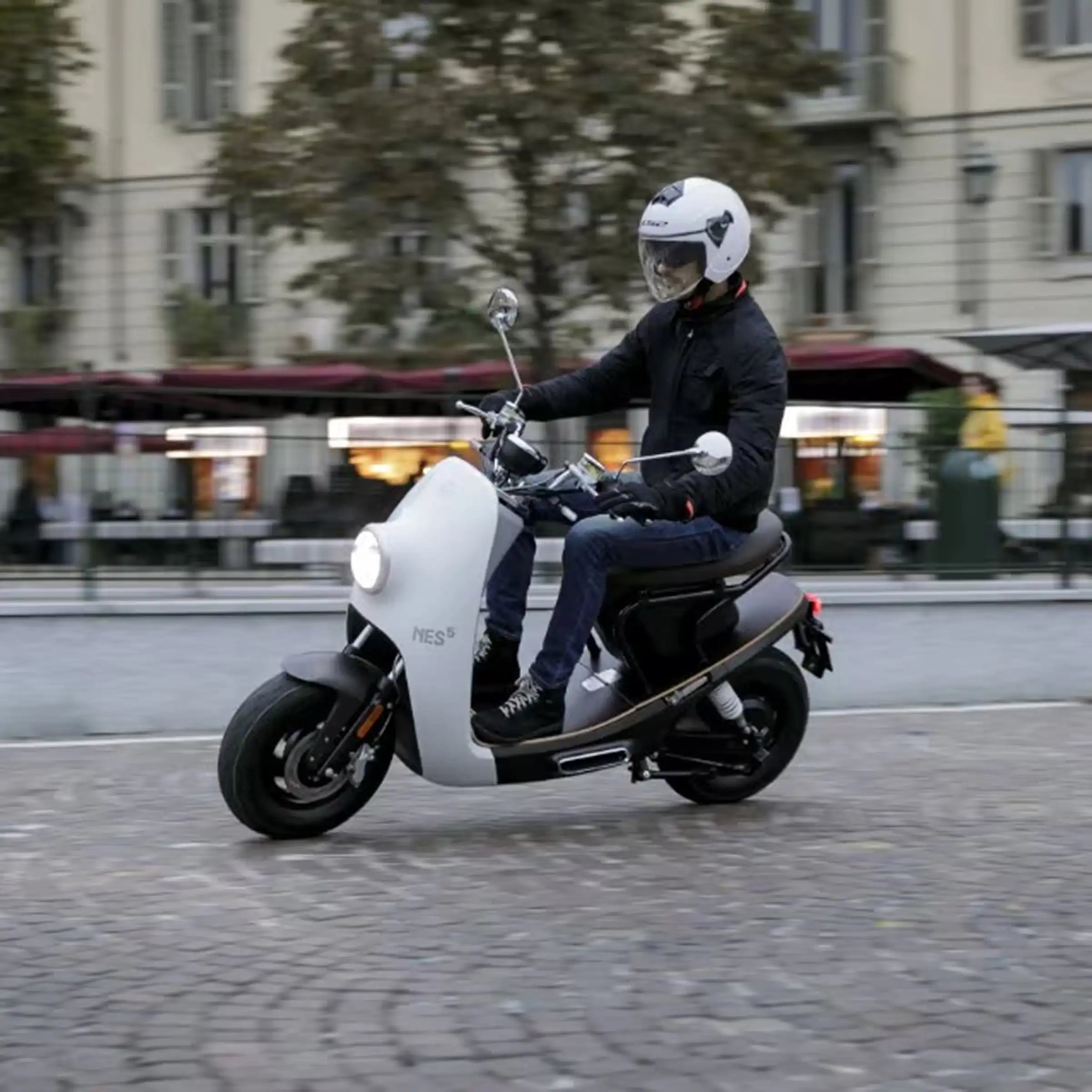 NITO NES 5 elektromos robogó használat közben városi környezetben, fehér karosszériával és barna üléssel.